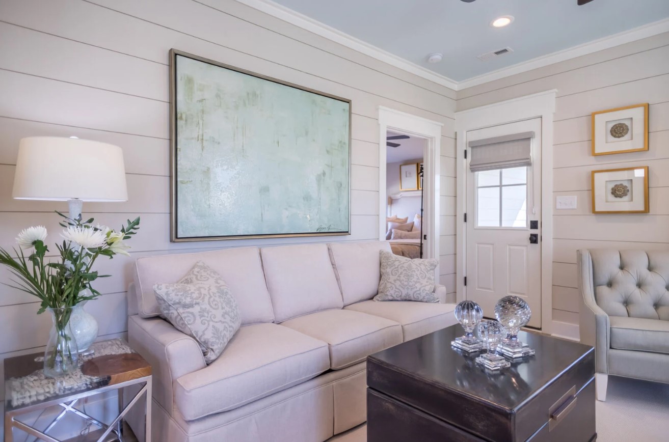 living room with a white couch, light blue art work, brown table and a white bouquet