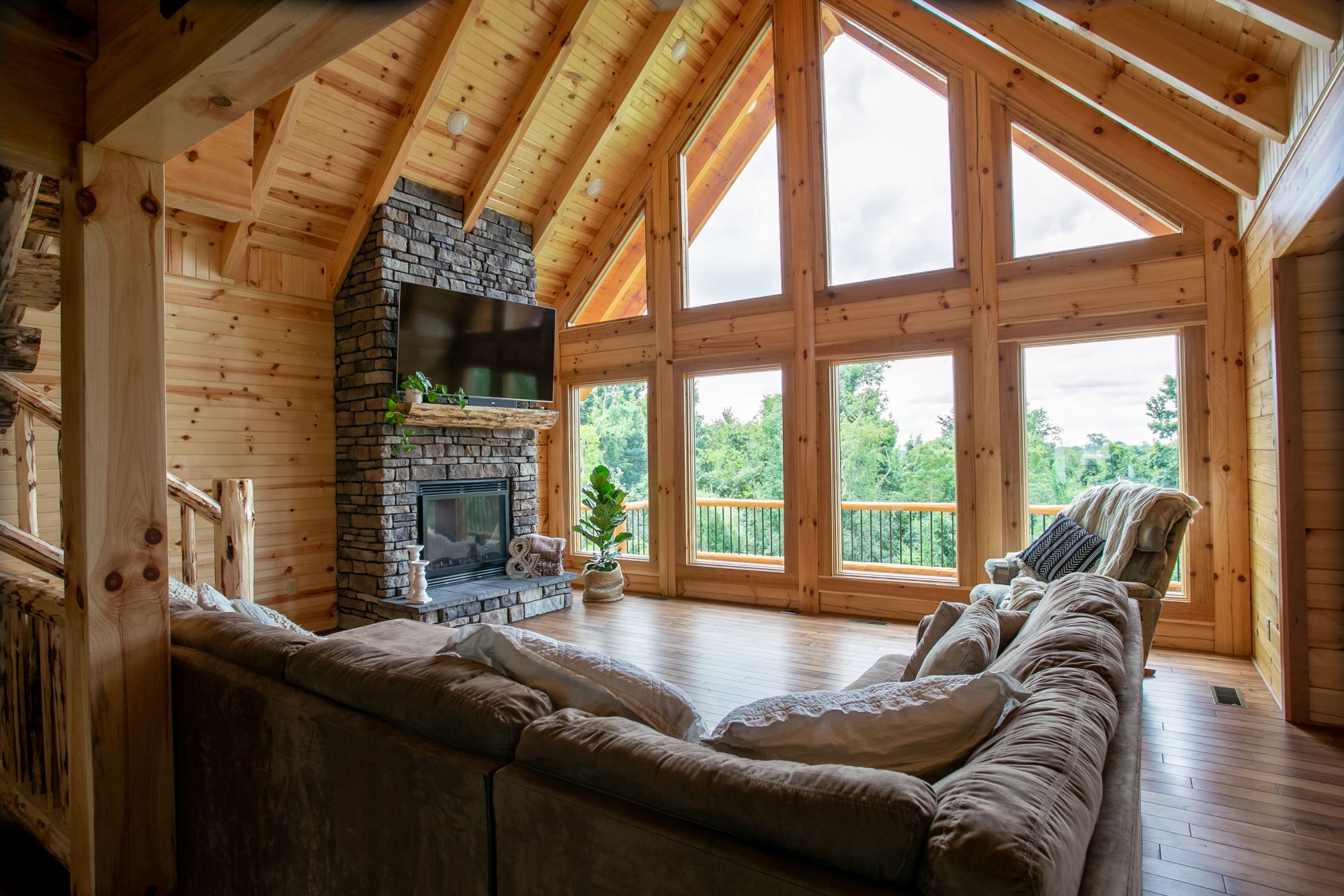 living room with an l-shaped couch, floor to ceiling windows, flat screen tv and a fireplace