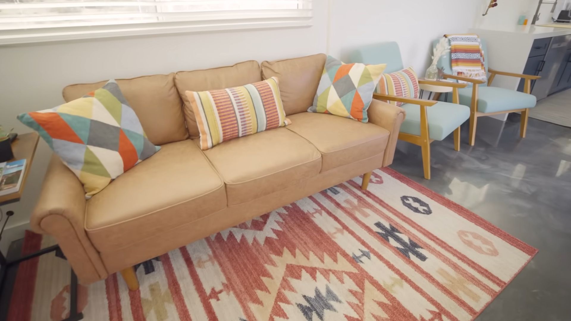 living room with a light brown couch, light blue armchairs, colorful pillows, and a rug