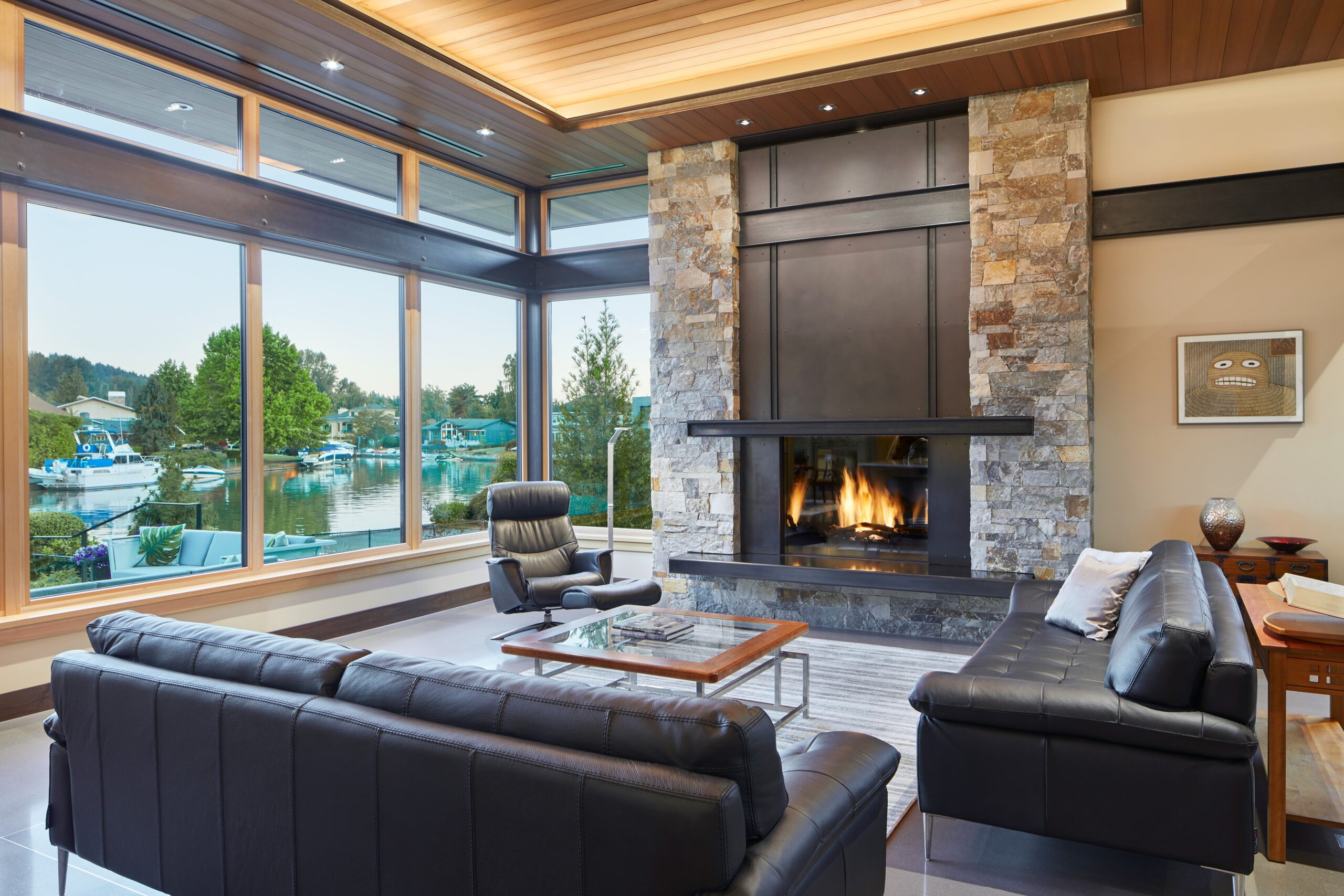 living room with black, leather couches, floor to ceiling window, small glass table and a fireplace