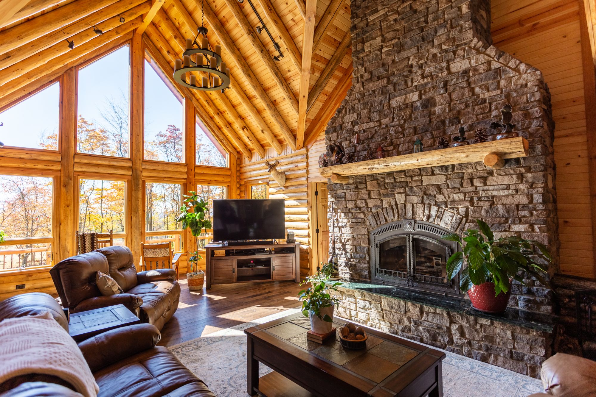 living room with leather couches, flat screen tv, fireplace and floor to ceiling shelf, and brown table