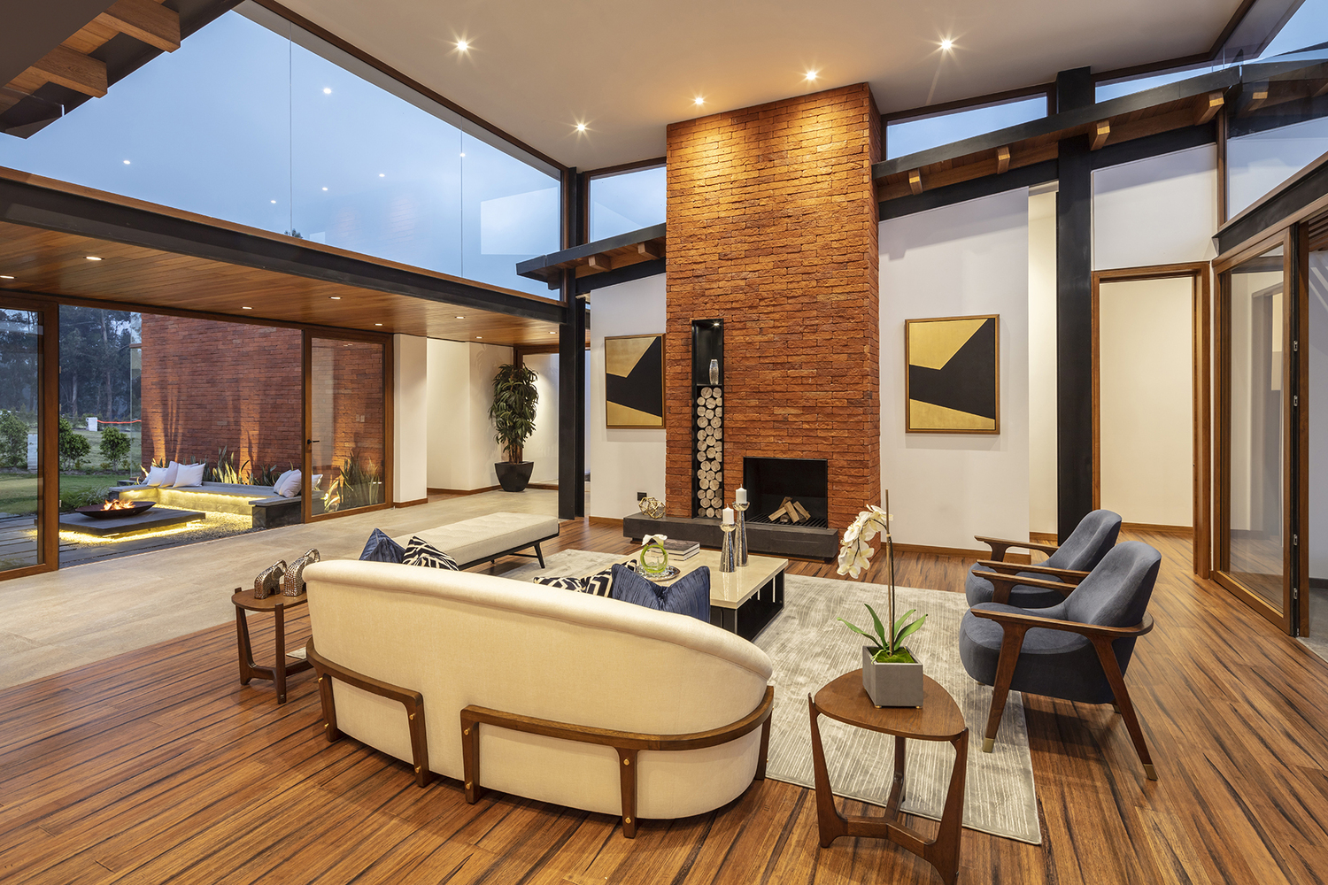 living room with a white couch, blue chairs, a cushioned bench, a small table, fireplace and artworks