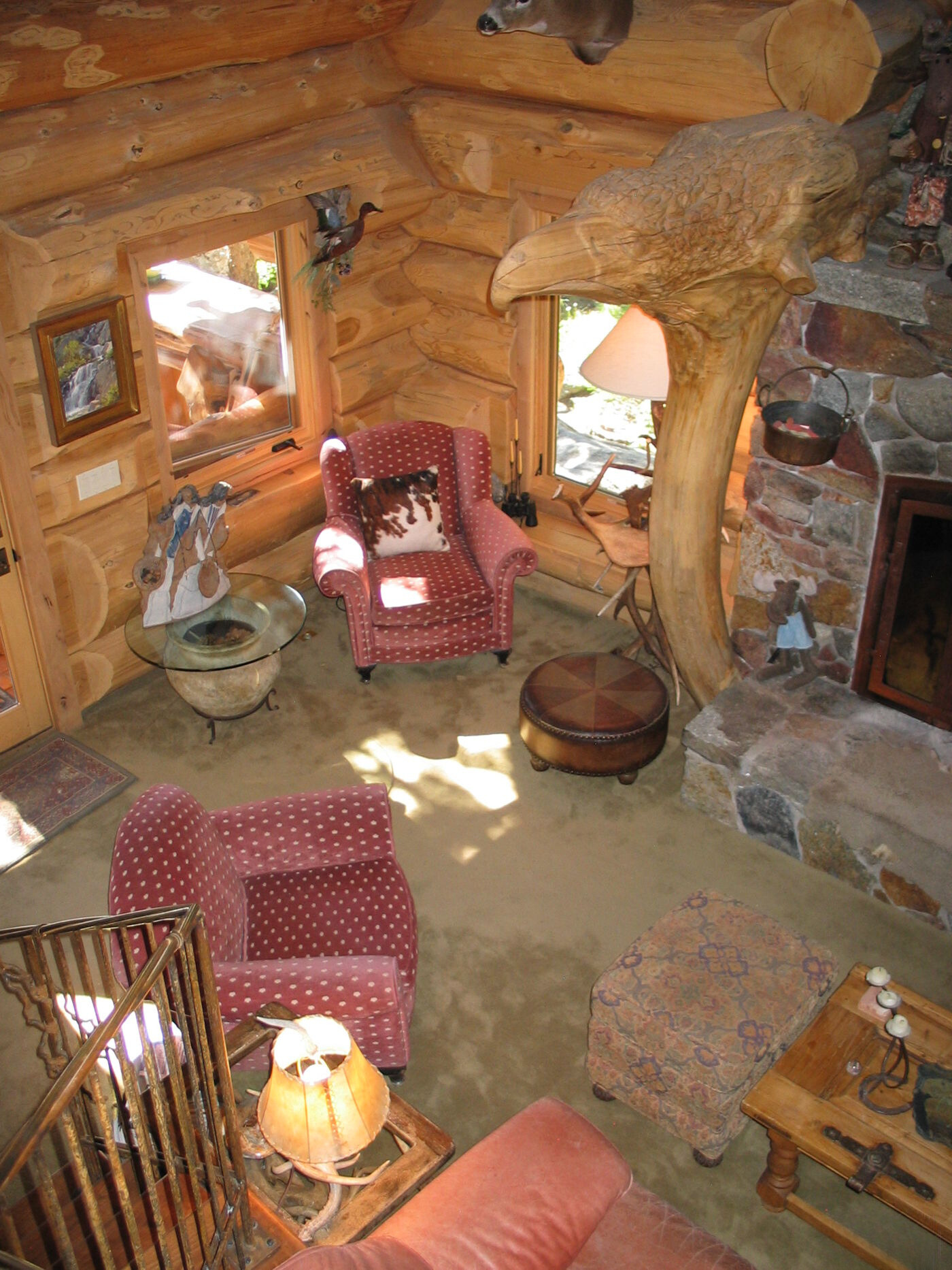 living room with red chairs with white dots, orange couch, brown, wooden walls with windows around