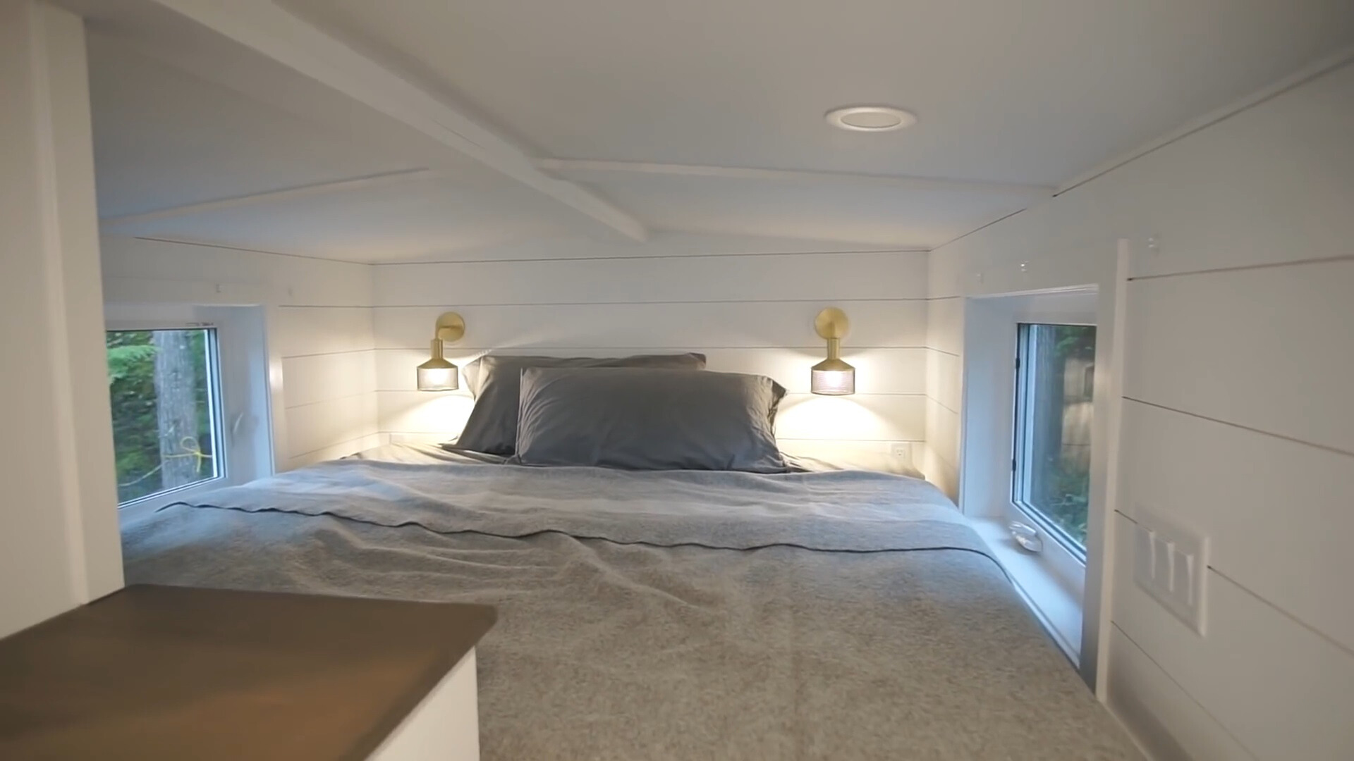 king sized bed with windows on two walls in a loft area