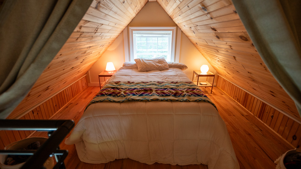 loft bedroom with a bed in the middle and bedside tables with lamps on the side and a mirror above the bed