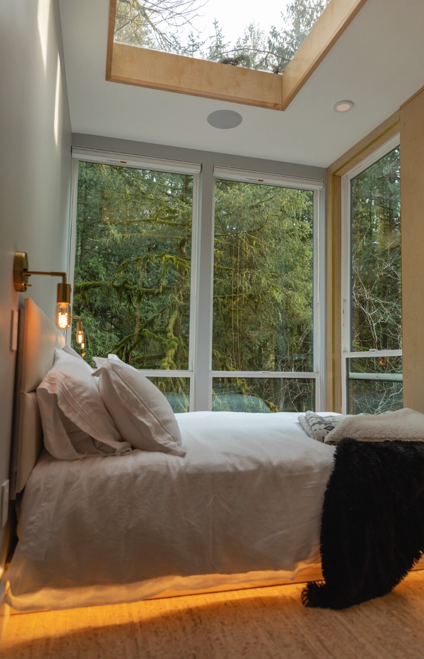 master bedroom in a container home with large windows and a sky light