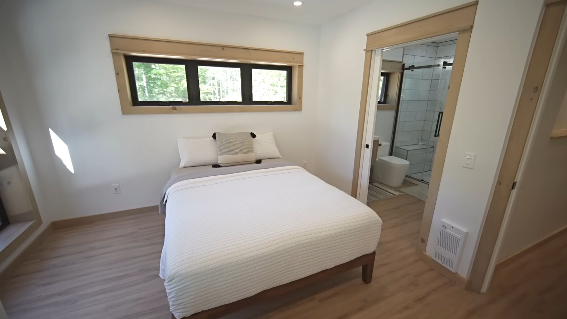 master bedroom with a big bed in white and three small windows above it