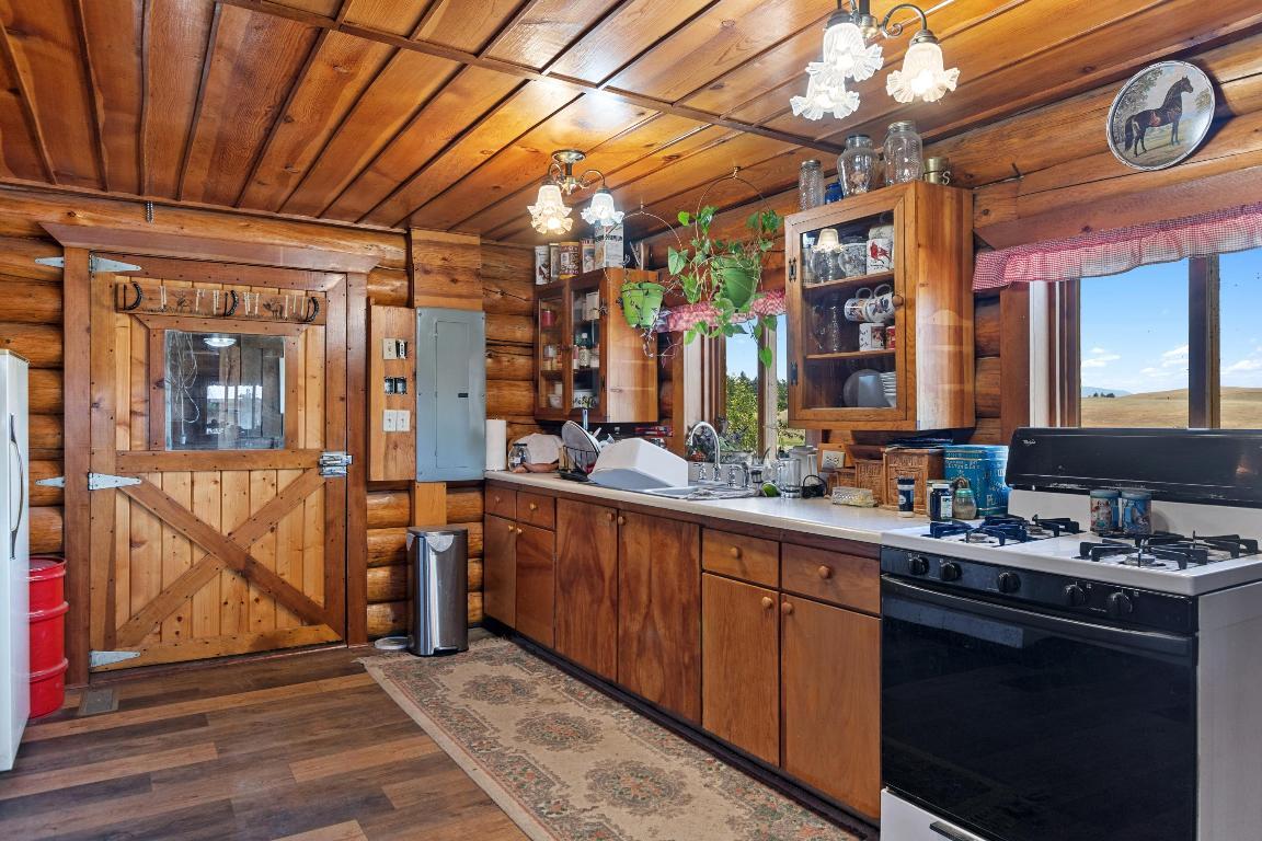 kitchen with wooden walls and brown cabinets and a lot of dishes