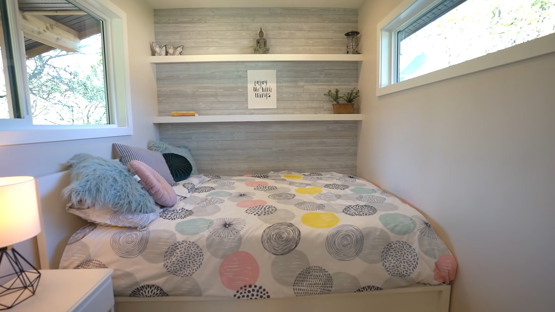 bedroom with two windows, white shelves and a white bedside table with a lamp