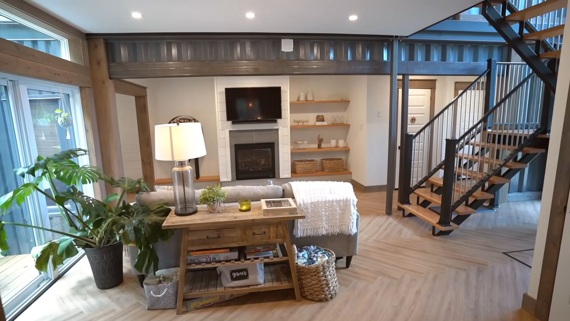 open concept living room with a modern fireplace and TV above it, with staircase adjacent