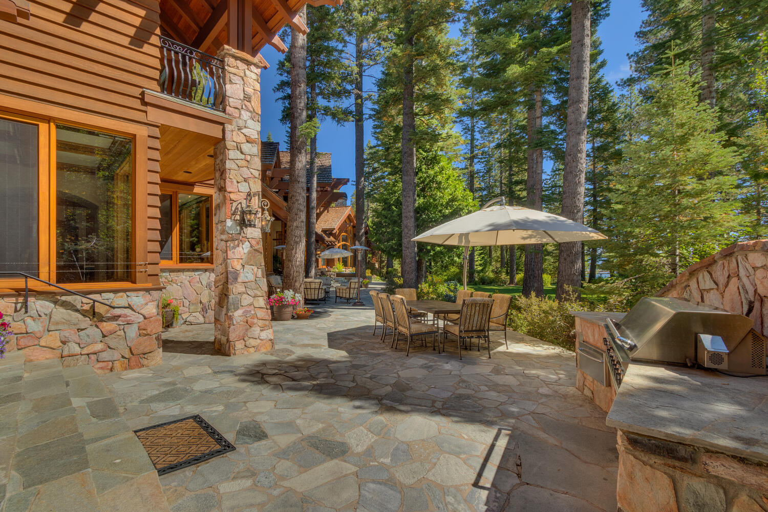 outside area of a cabin with a table surrounded by chairs and an outside grill