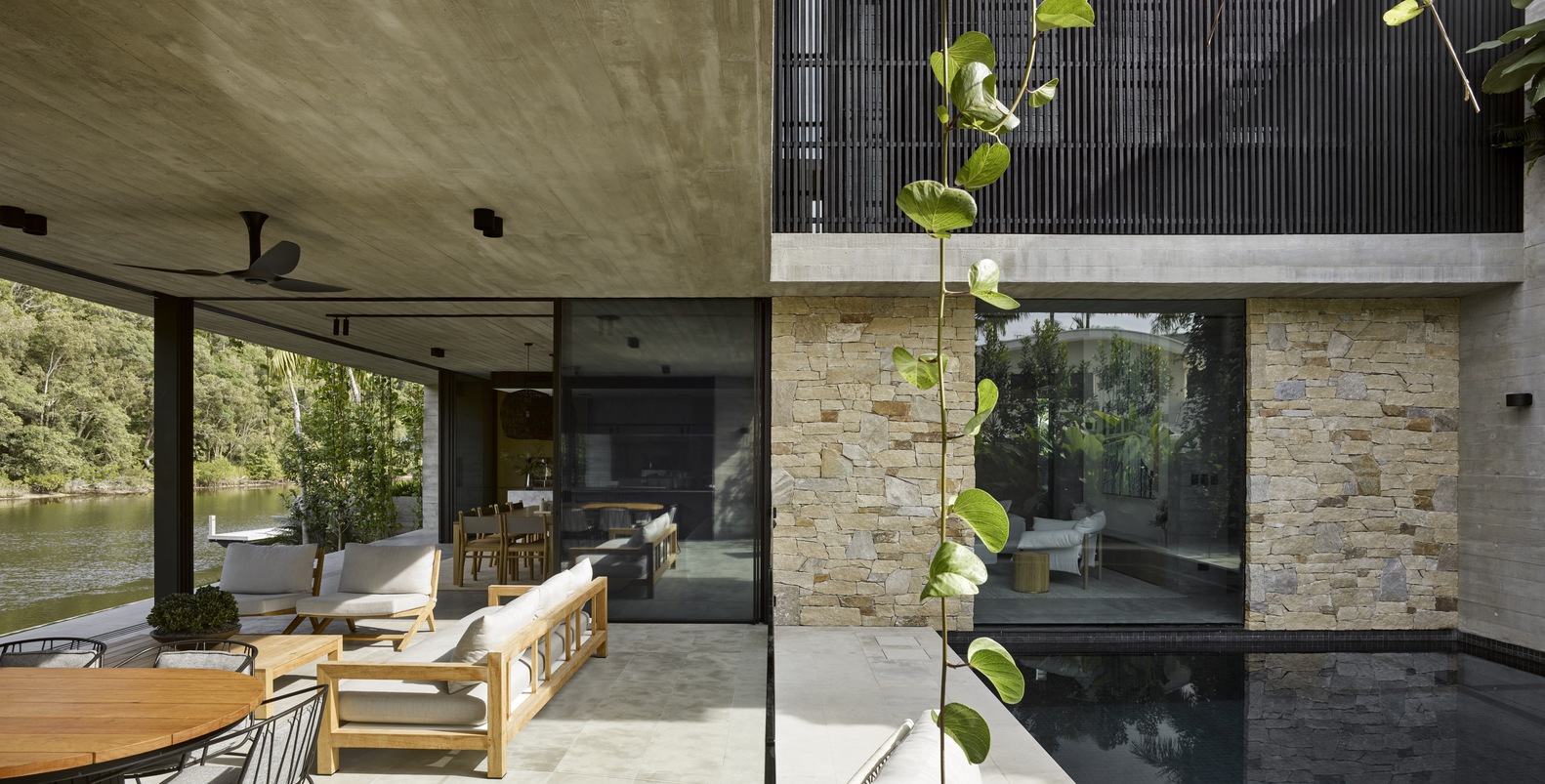 outside area of a modern house, with a furnished couch and chairs and a pool on the right