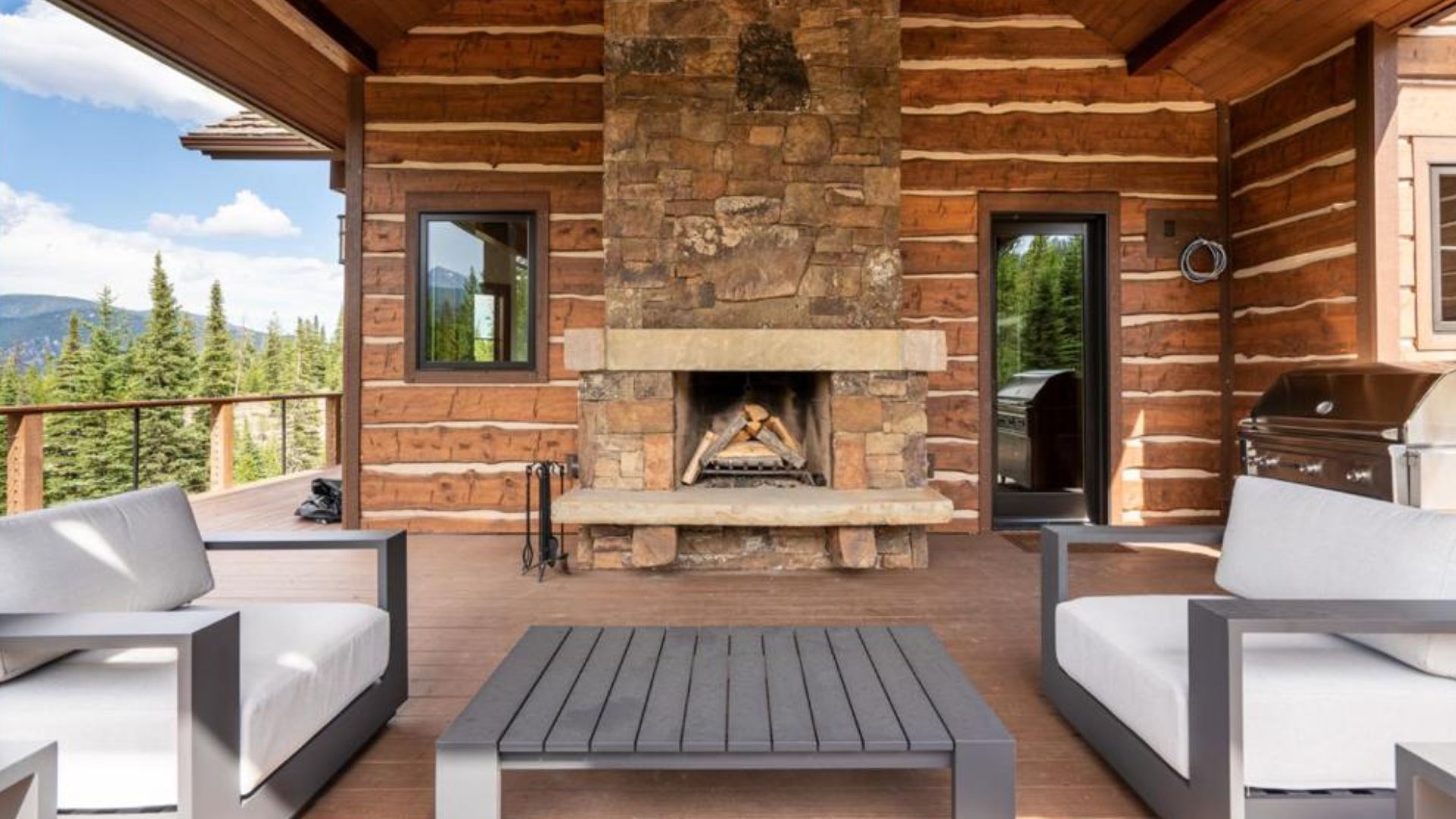 outside sitting area on the dec with a big fireplace and a grill