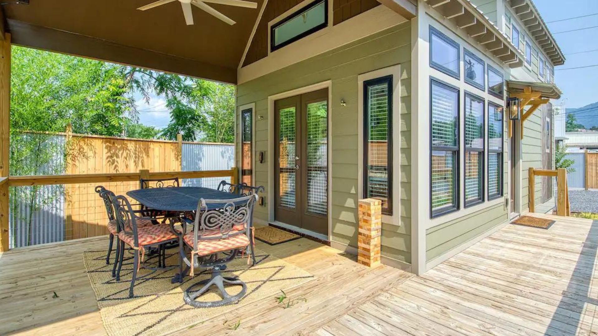 tiny green house porch with a set of chairs and a table in sunlight