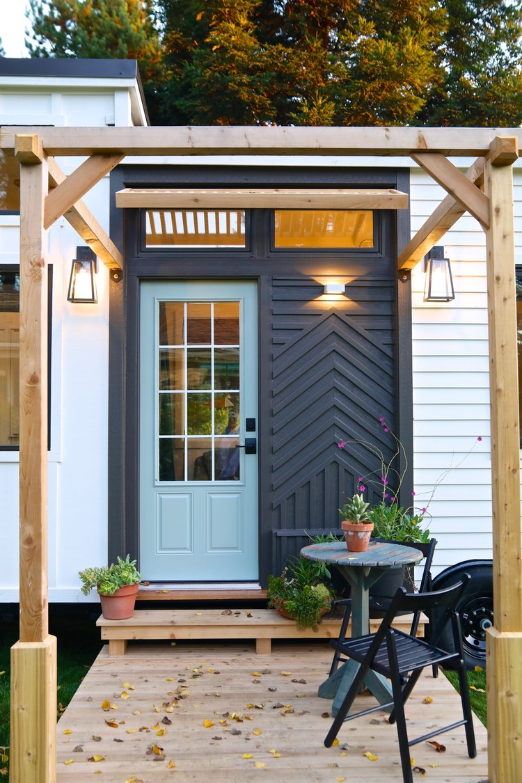 small porch with a small black table and black chairs, light blue entry door