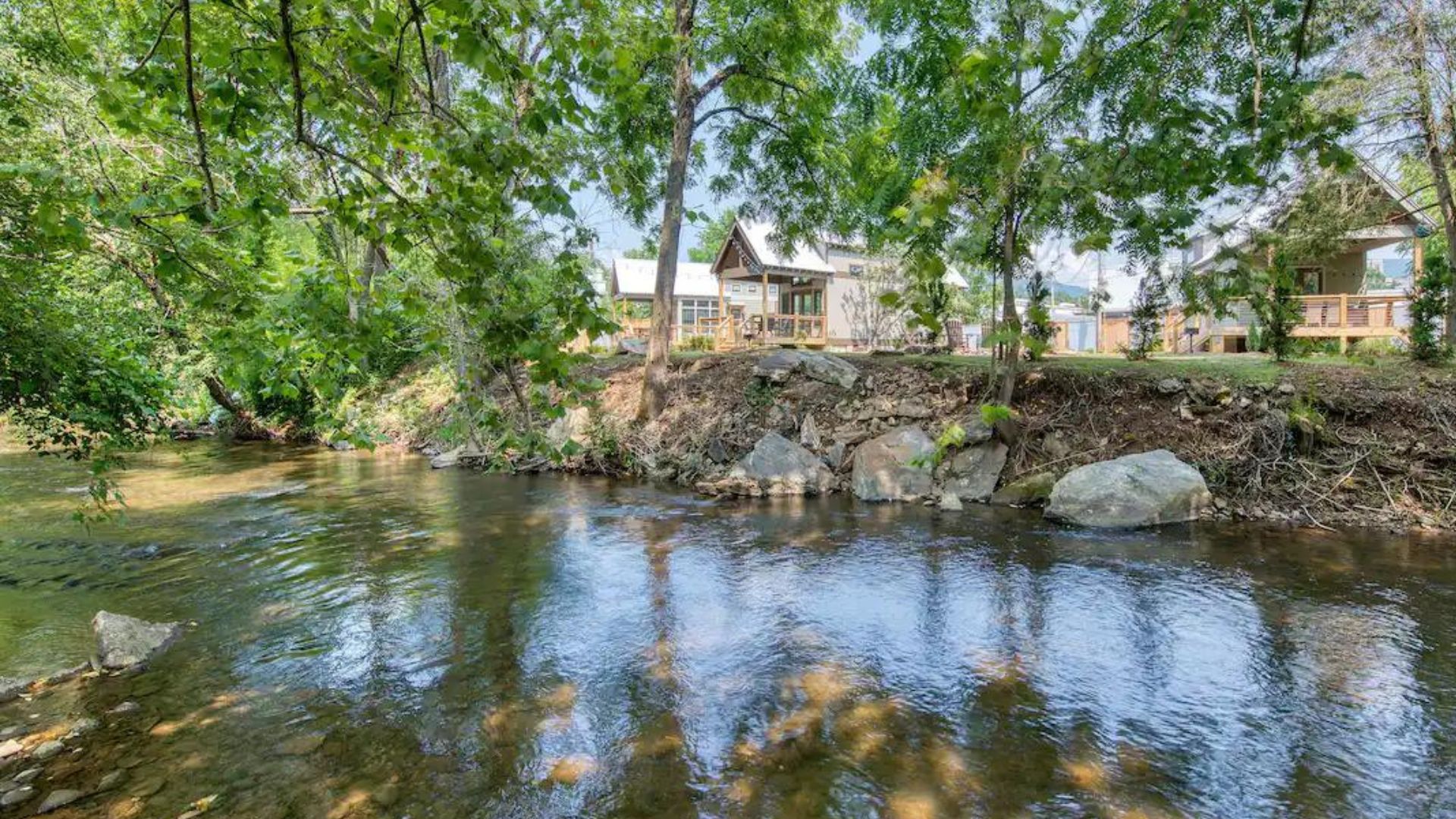 beautiful river next to the three tiny houses surrounded by trees