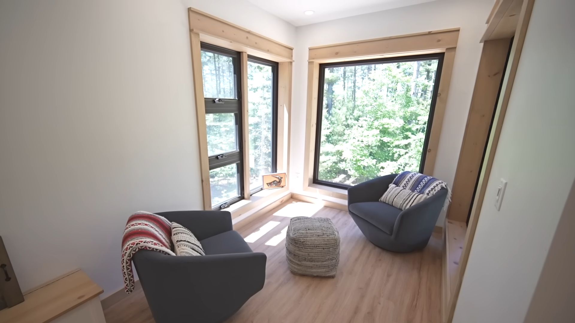 a sitting area in a living room with two armchairs and picture windows for the view