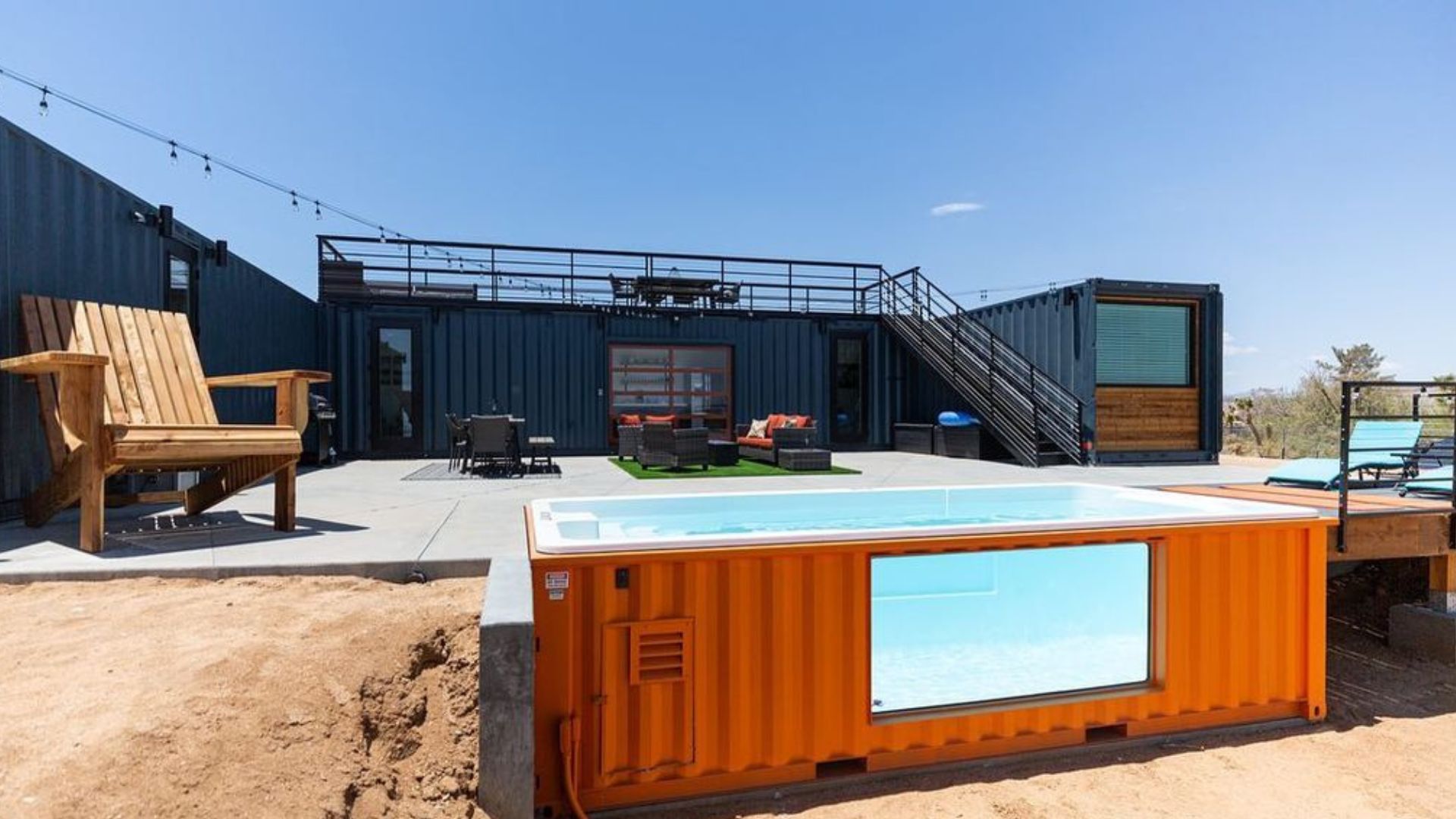 cool orange swimming pool made of a container and a huge wooden chair next to it