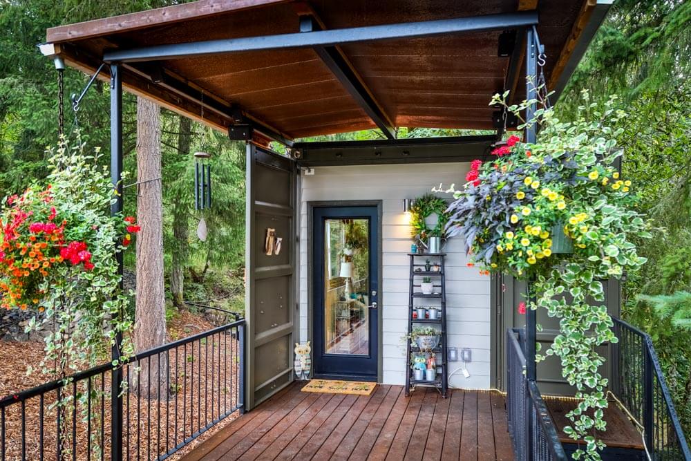 a terrace outside of the house with a ladder with flowers on it, flowers hanging around the house