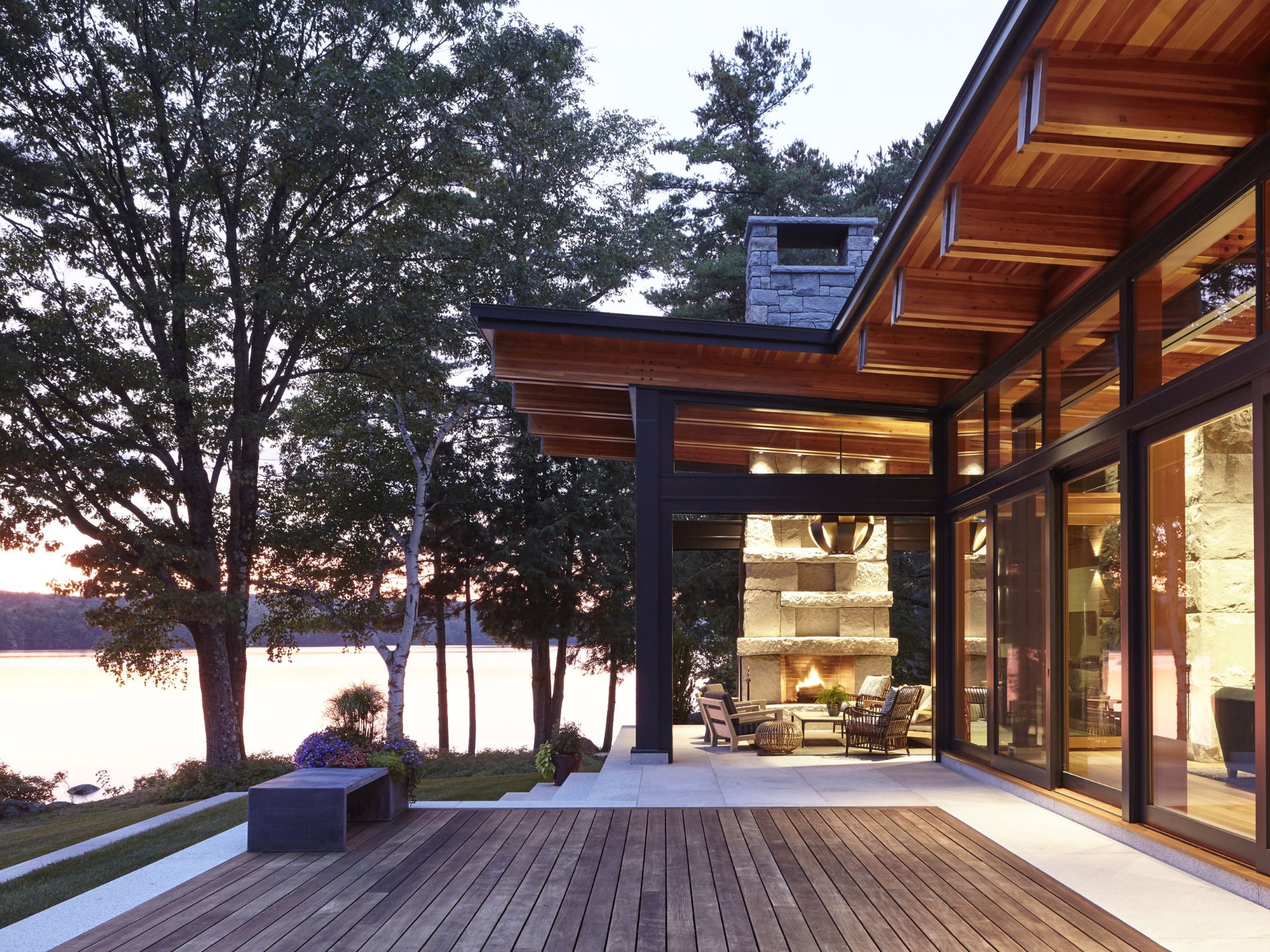 modern house with glass wall overlooking the lake and a fireplace sitting area