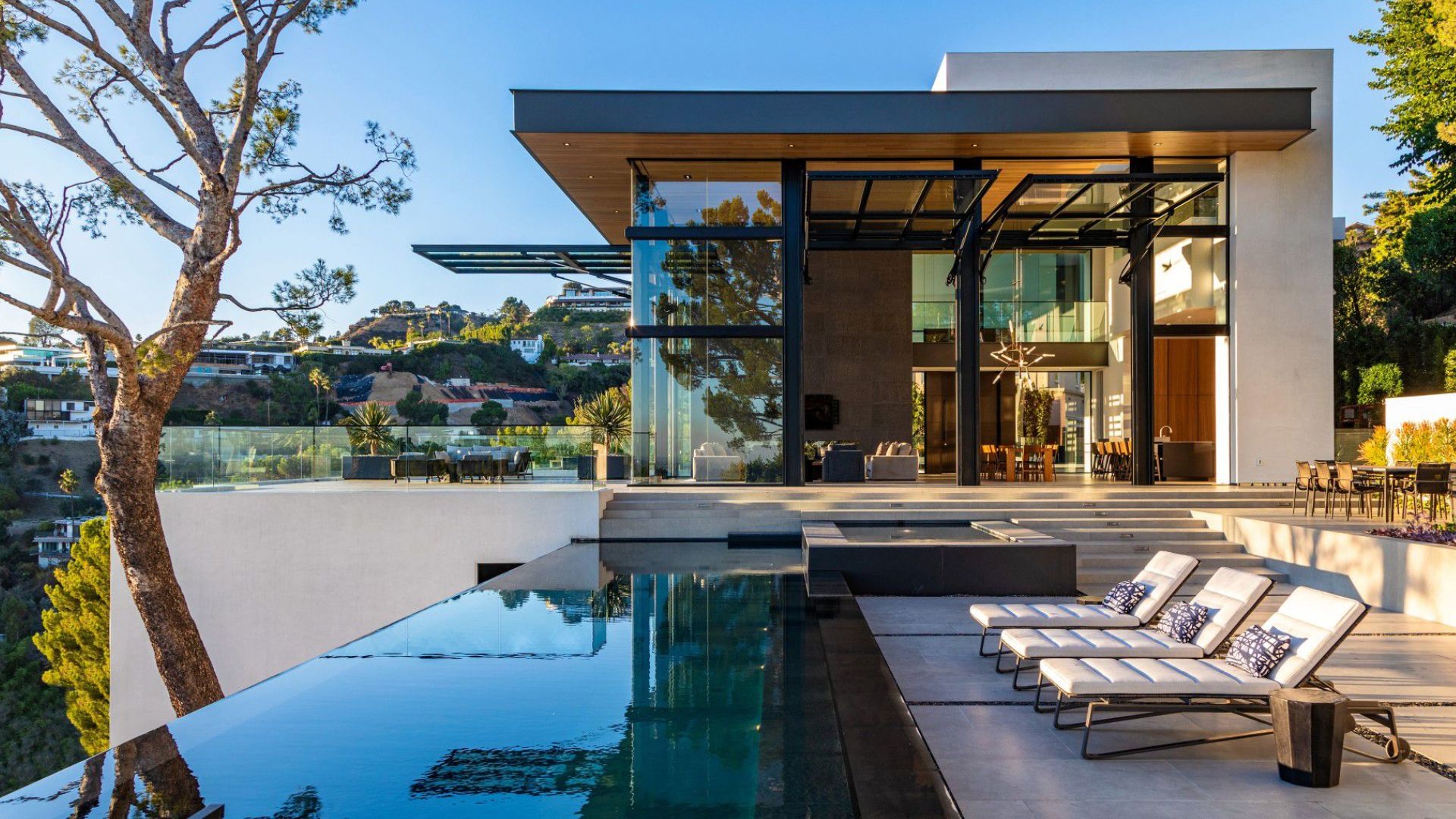 big terrace with a dining table, lounges, a hot tub, and an infinity pool