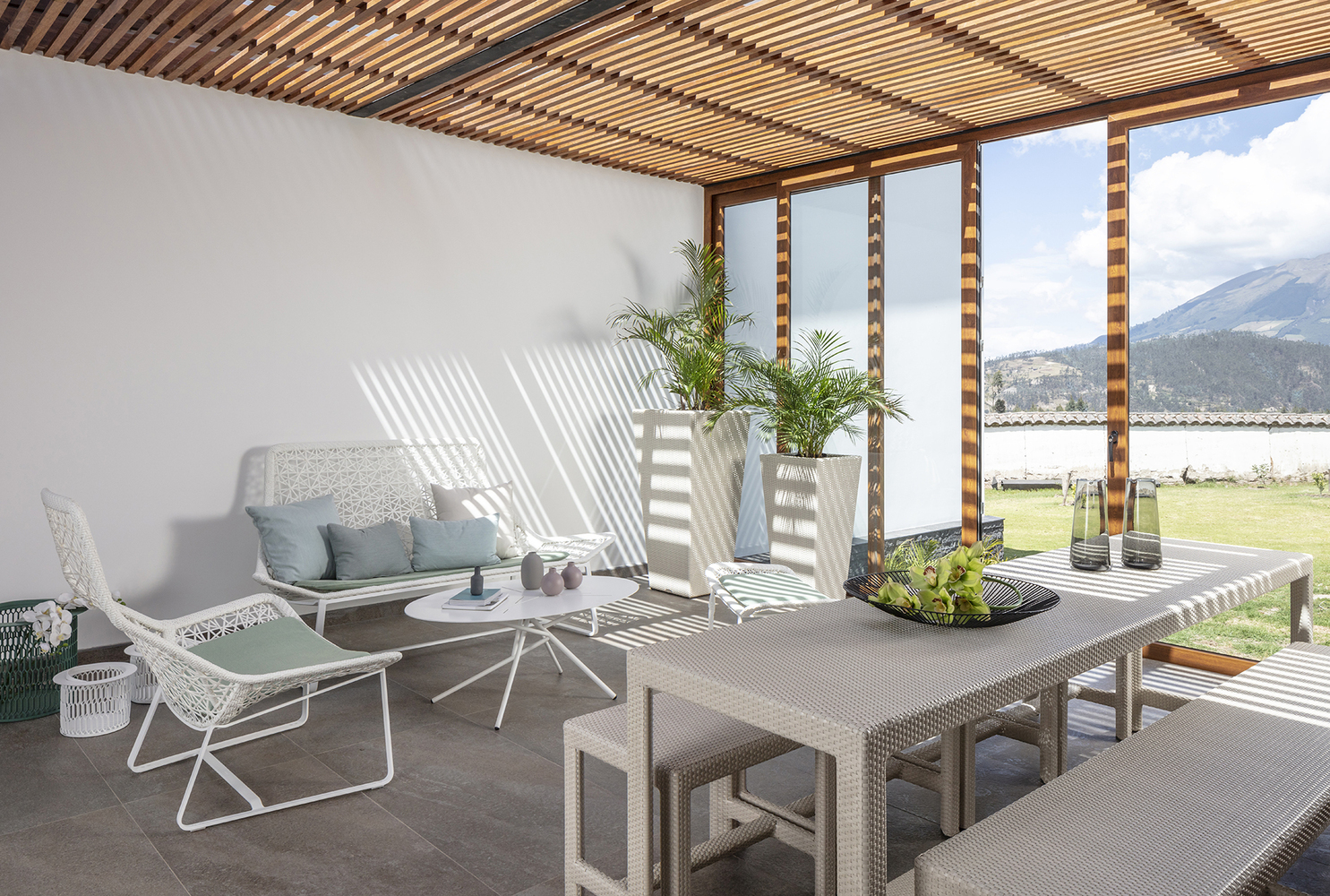 terrace with white bench and white chairs and a small white table, and a gray dining table with two benches