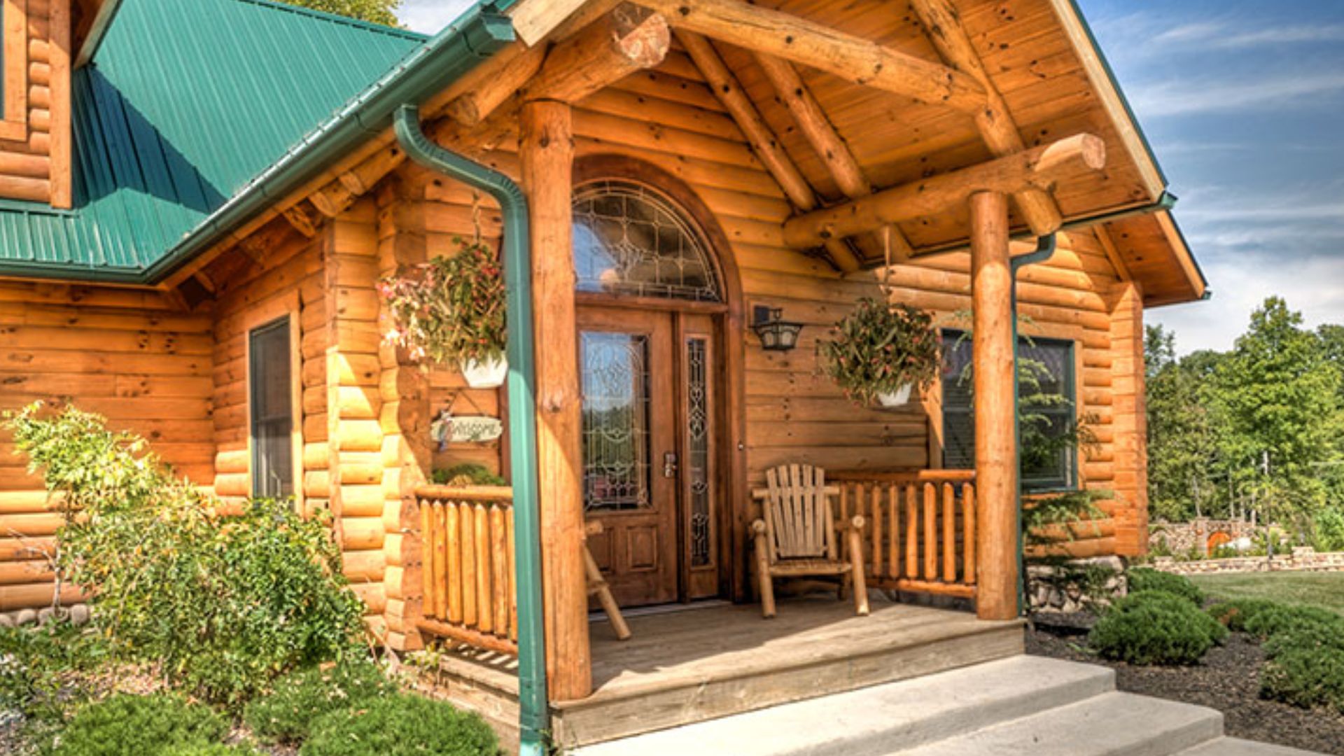 the entrance into clear fork log home made of wood logs with a green roof, surrounded by greenery