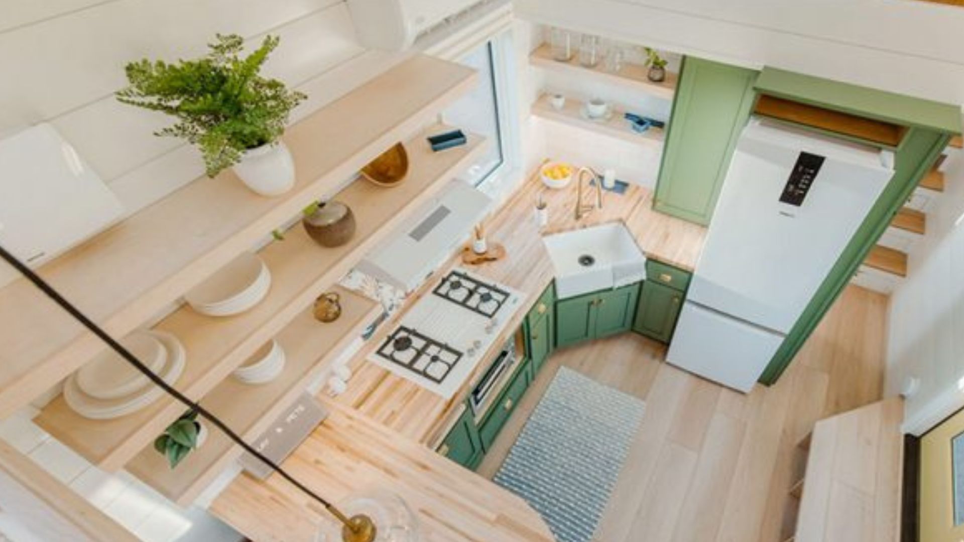 photo from above of the tiny house with green kitchen, shelves, and a round dining area