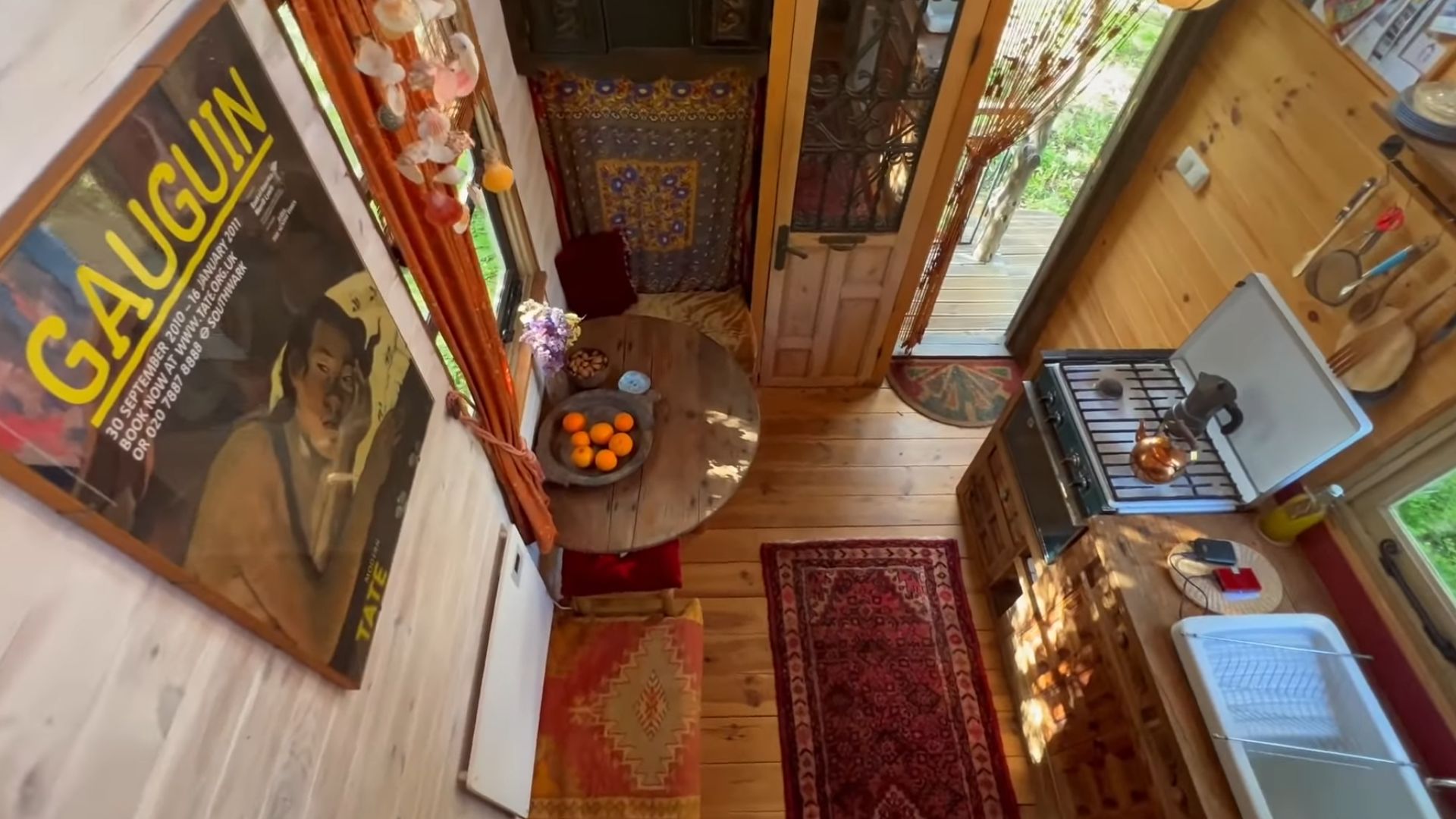 kitchen and dining agrea photographed from the loft, a poster on the wall, and lots of warm wood and red tones