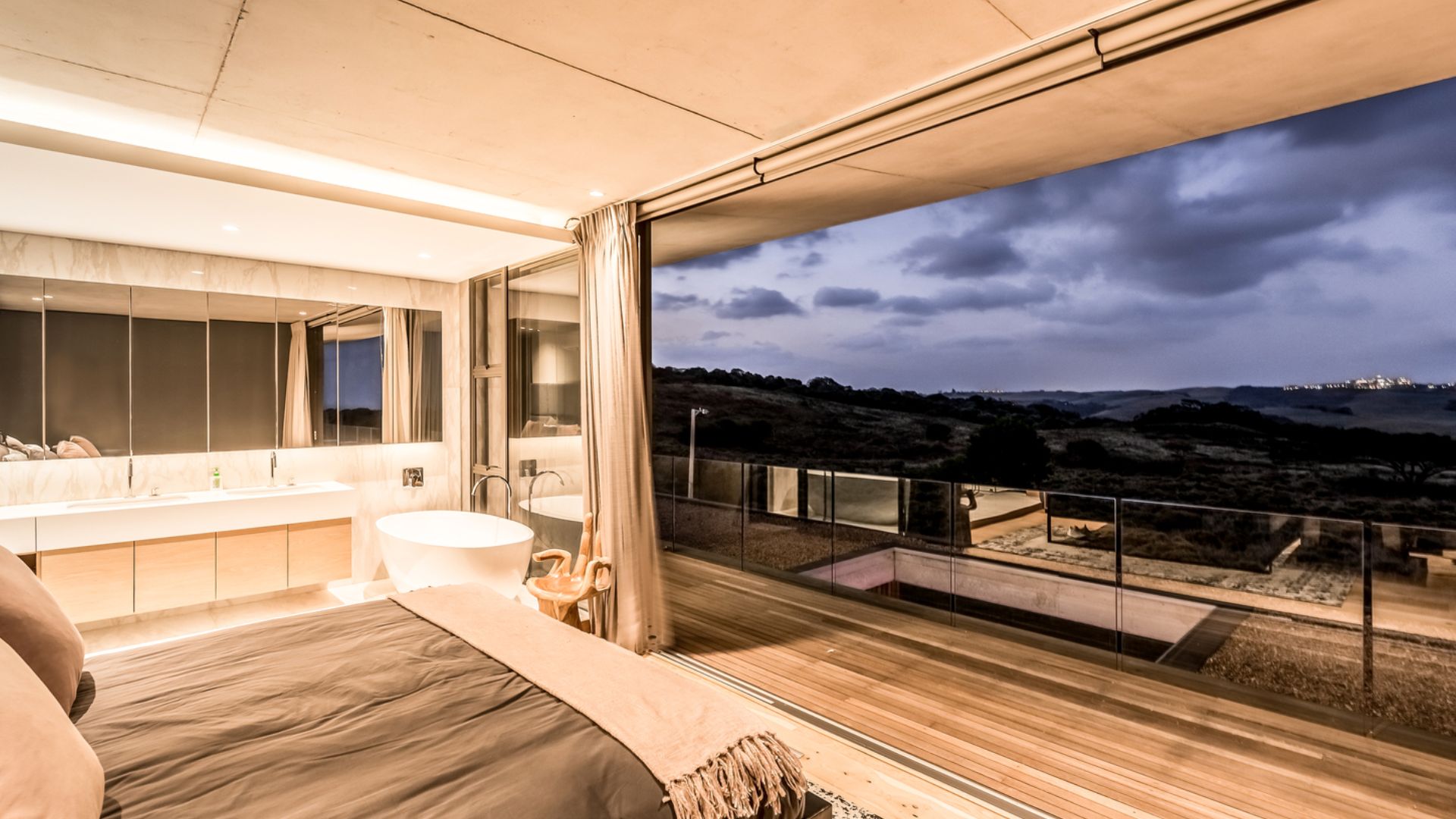 view from the bedroom through open glass walls, and a big comfy bed in grey