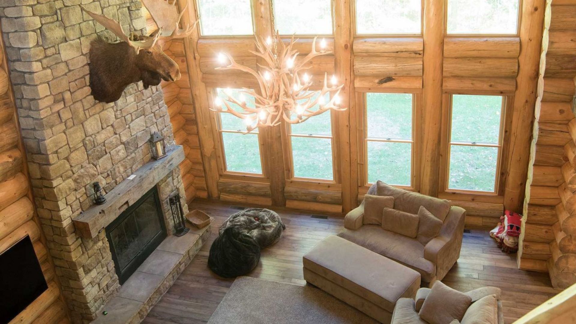 view from the gallery overlooking the living room area with a huge fireplace and antlers chandelier