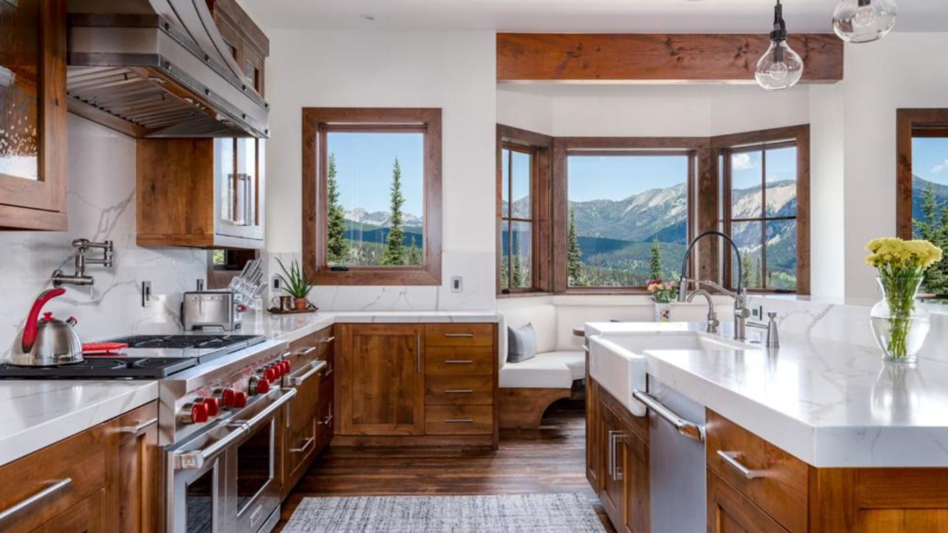 walnut wood kitchen with modern appliances and a window nook with a dining set