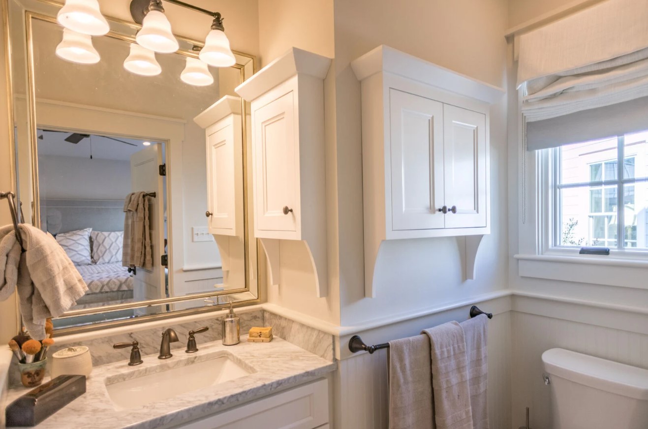 bathroom with white cabinets, big mirror and a marble countertop