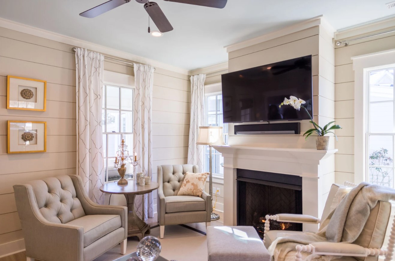 living room with white walls, white curtains, a flat screen tv and a fireplace