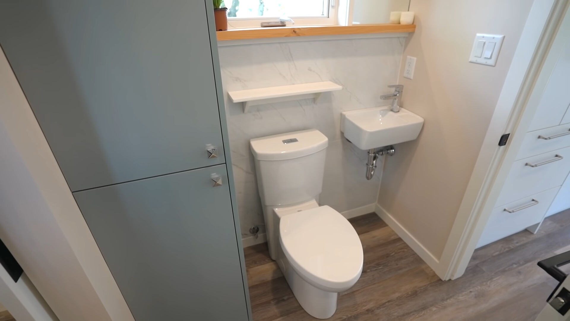 bathroom with a white toilet, white sink and gray cabinet