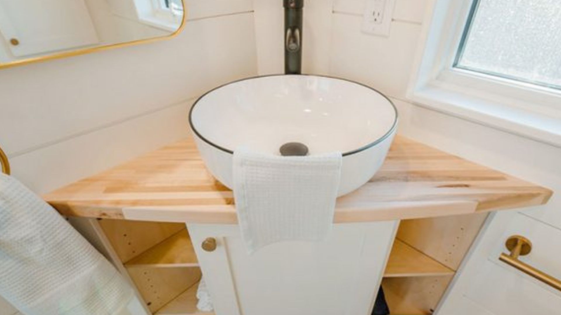 wooden vanity in the corner with a round sink and black faucet