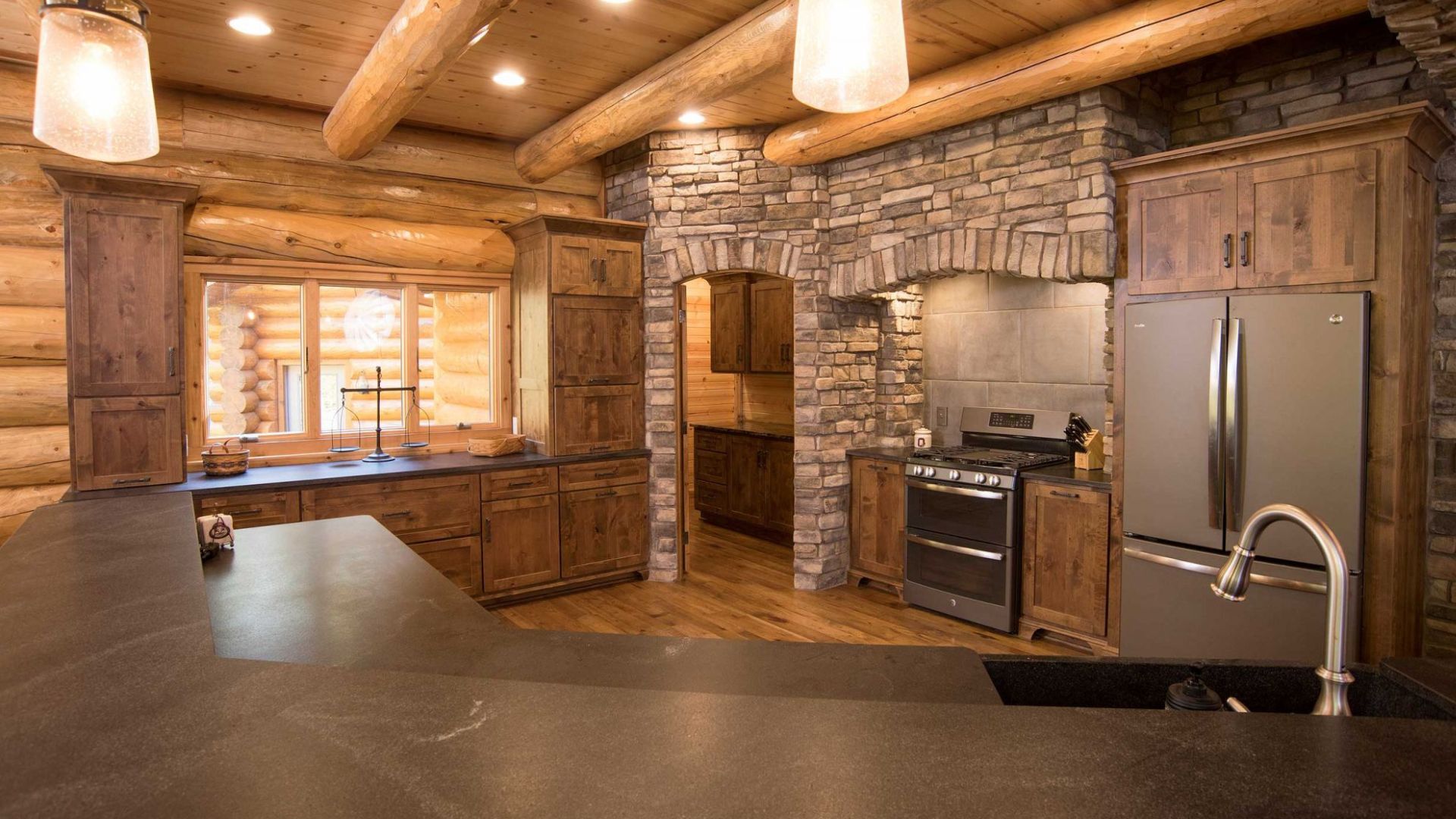 kitchen with wood cabinets blending in with the walls, graphite appliances, and stone details on the walls