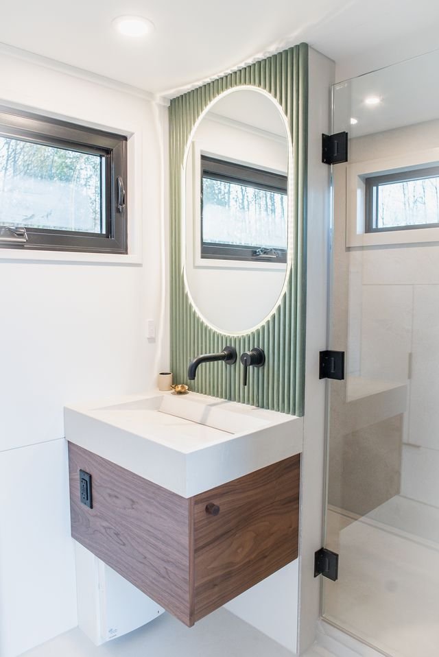 Bathroom in tiny house with floating vanity and green mirror