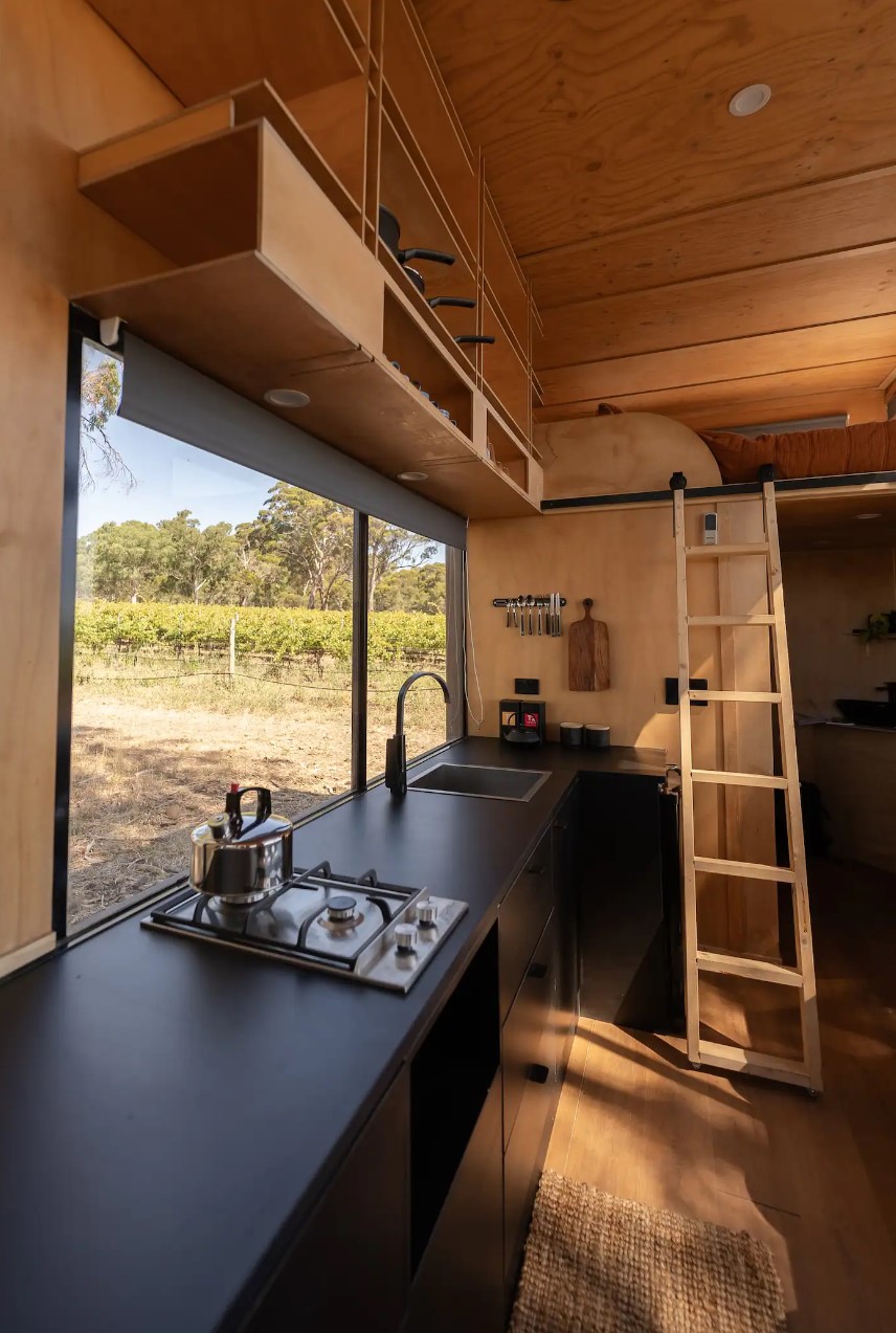 Black kitchen with a large window and exposed shelves