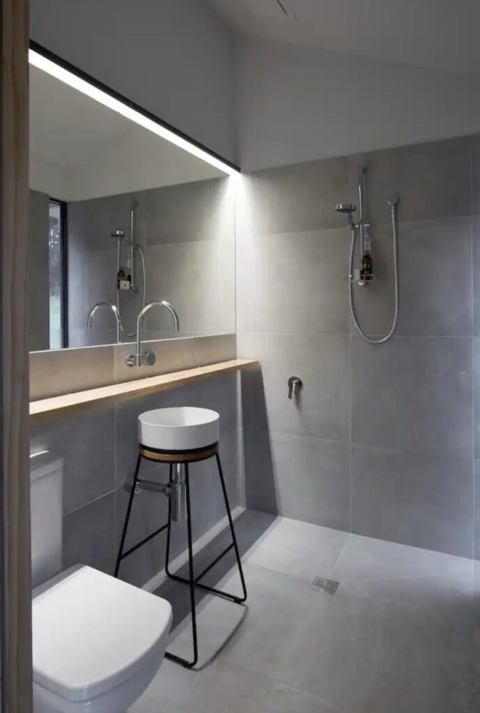 Gray minimalistic bathroom with a unique sink and big mirror