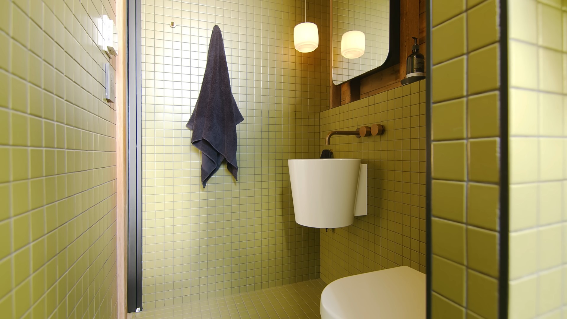 Green bathroom with a wooden backsplash and unique sink