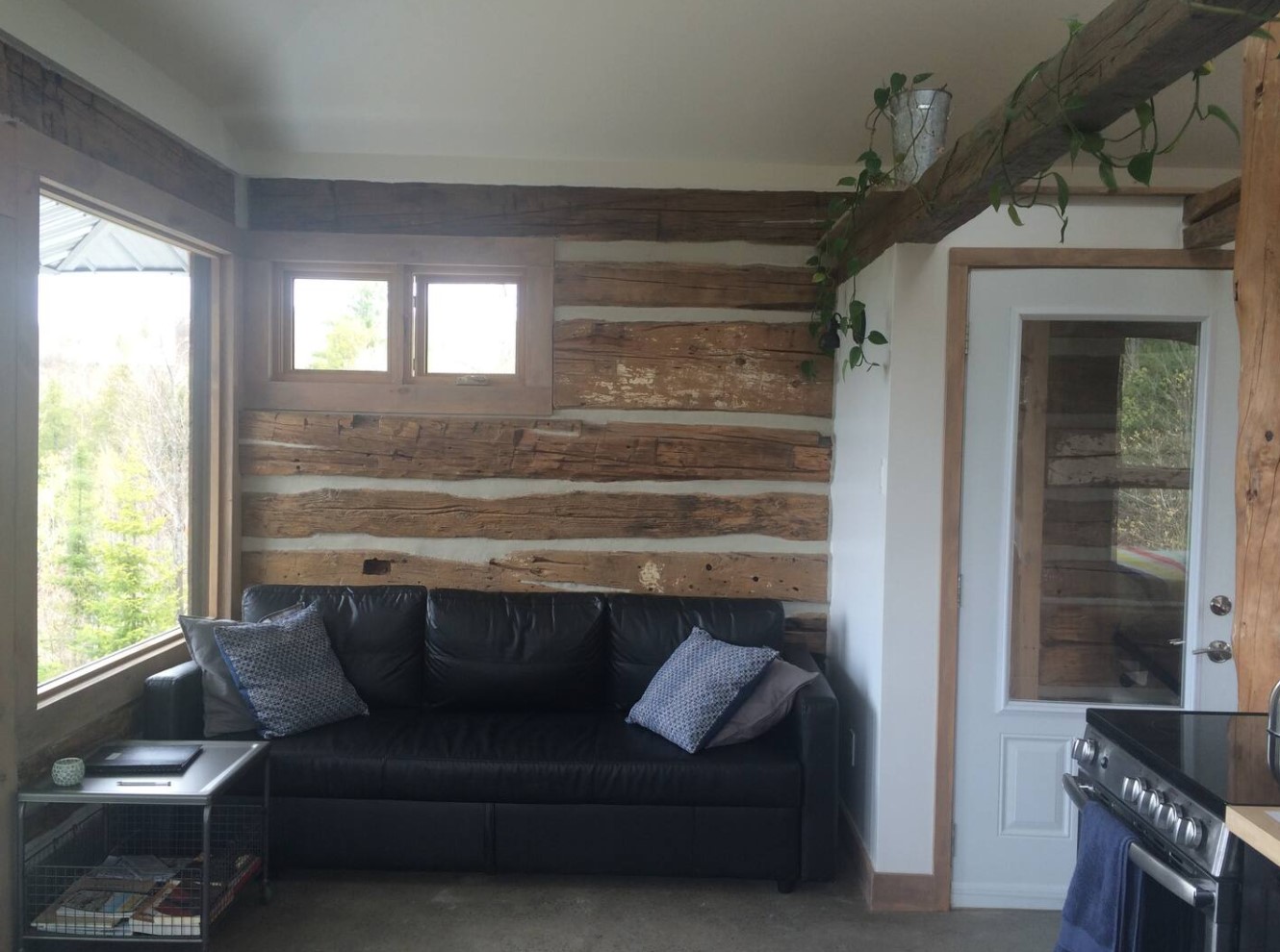 Living room with a black couch and wood on walls