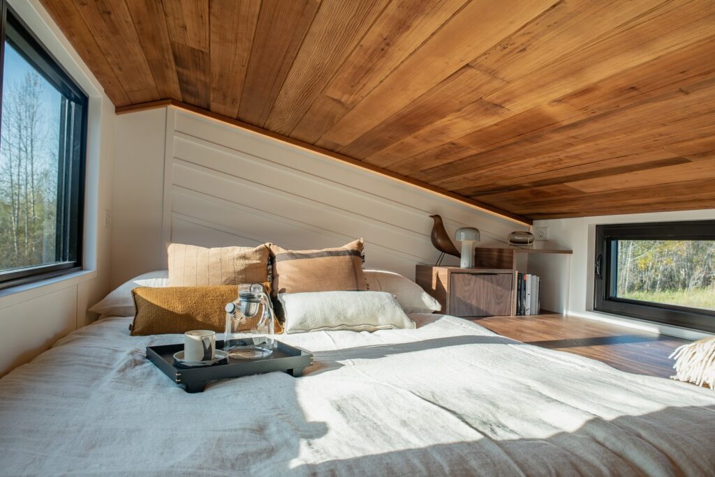 Loft area with a king-sized bed, two windows and wooden details