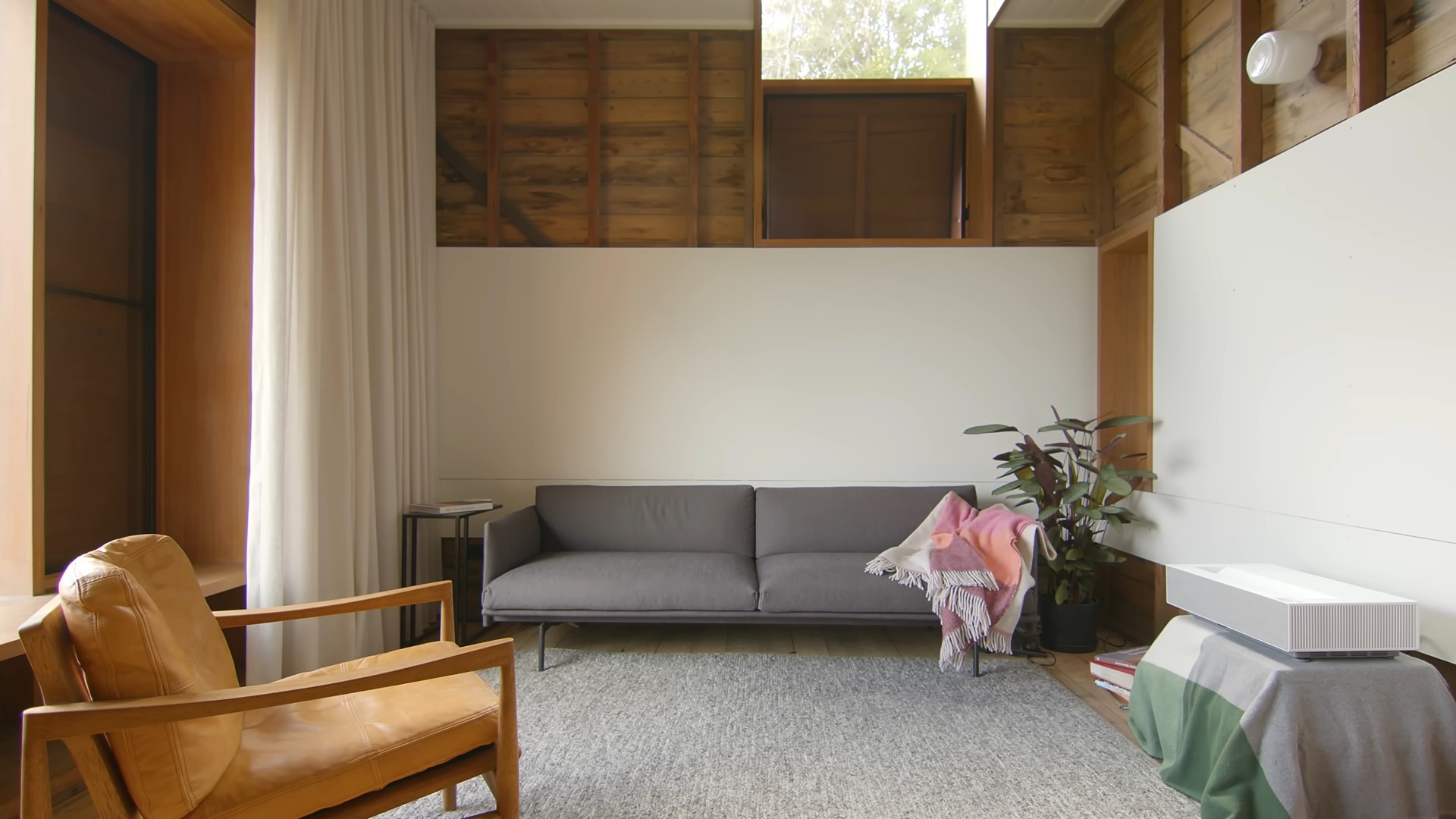 Mian living area with exposed wooden wall and gray couch and a carpet