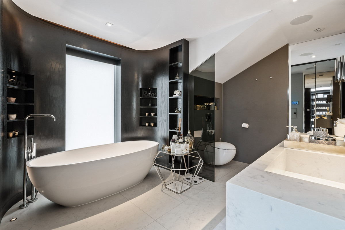 Master bedroom with curved black walls and a free standing bathtub