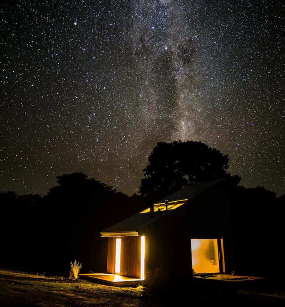 Small, modern lit up cabin under the stars