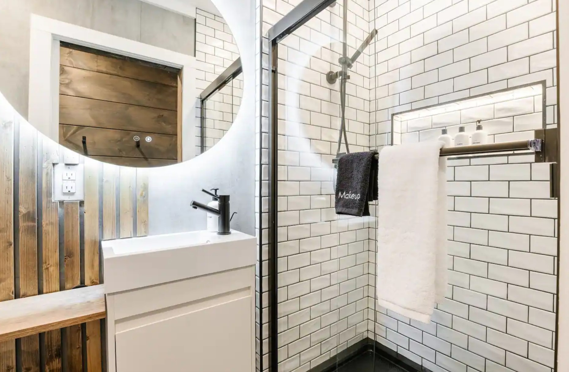 Small black and white bathroom with light up mirror, vanity and walk-in shower