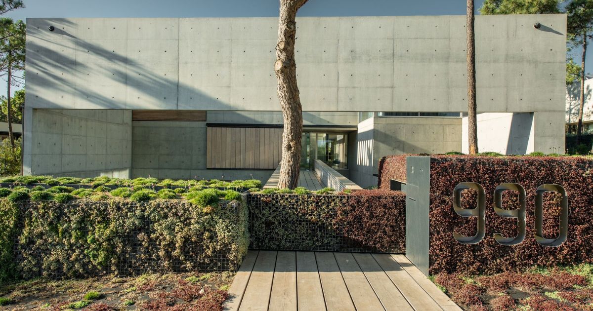 Concrete mansion with a fence with bushes poking out through