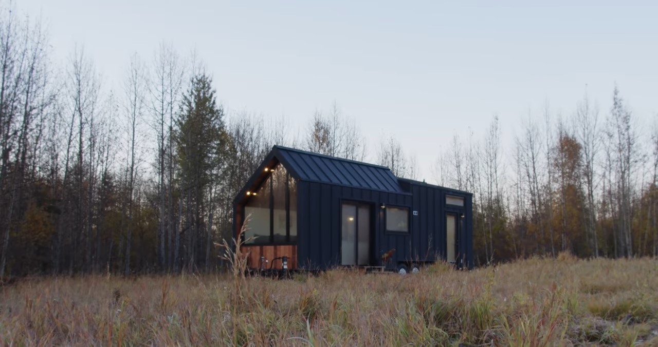 Tiny home in the middle of a field with tons of windows