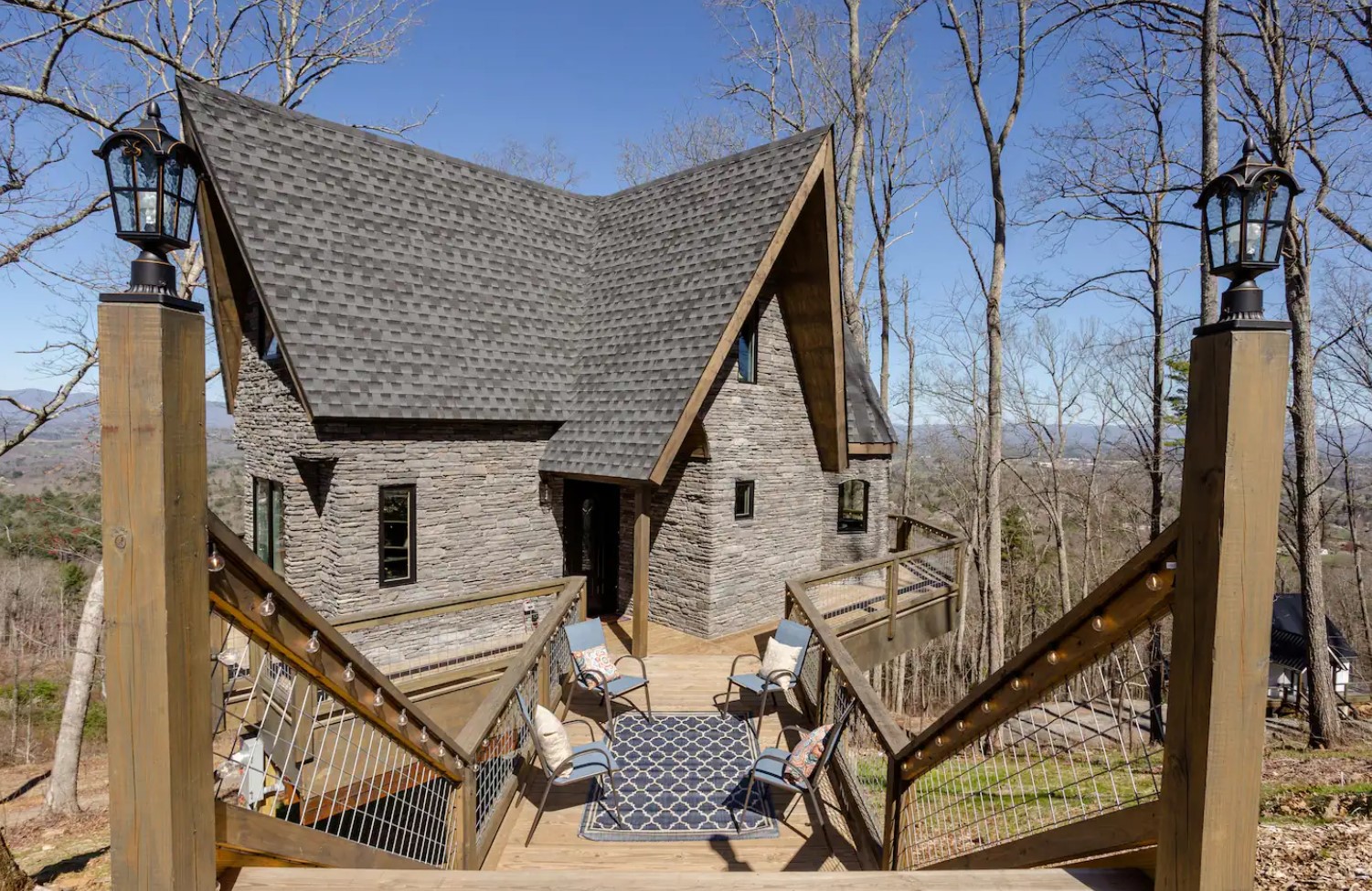 Stone treehouse with a wraparound deck and a lounge with blue chairs